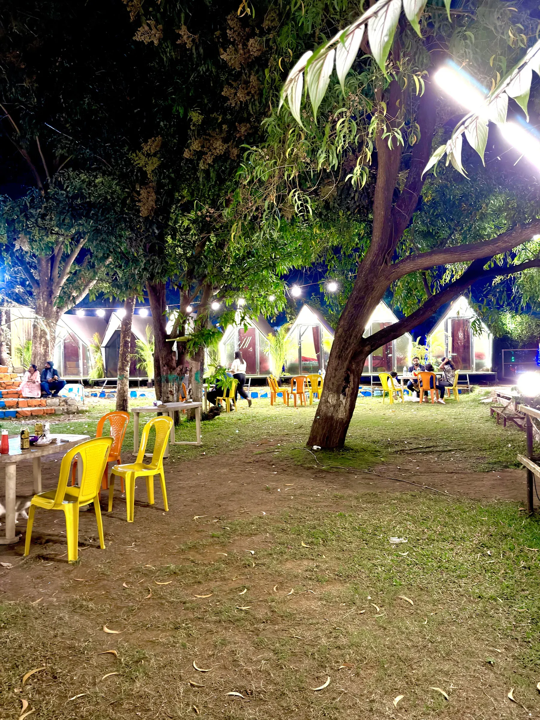 Guests relaxing at the illuminated Pawna Lake campsite at night